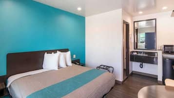 A hotel room with a bed, a desk, and a mirror.