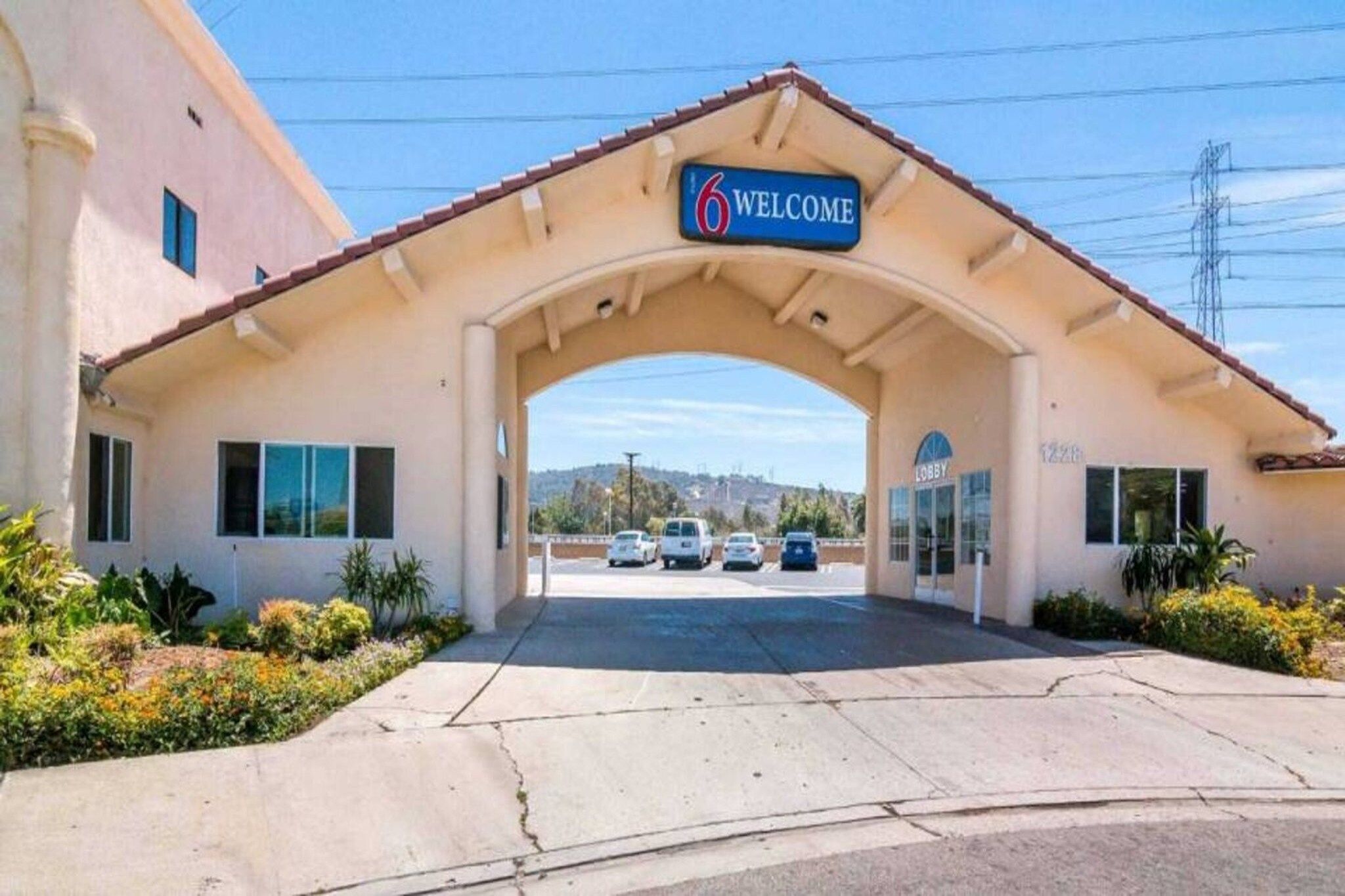 A building entrance with a 'Welcome' sign, a lobby, and a parking lot with cars.