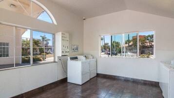 A laundry room with a washing machine, a dryer, and a large window with a view of the outside.