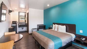 Habitación de hotel con cama, escritorio, silla, mesita y espejo.