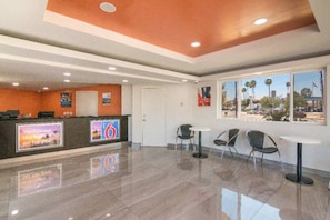A hotel lobby with a reception desk, a large window with a view, and a clean, tiled floor. - ADA Queen Bed|RI Shower|Nsmk (South El Monte)