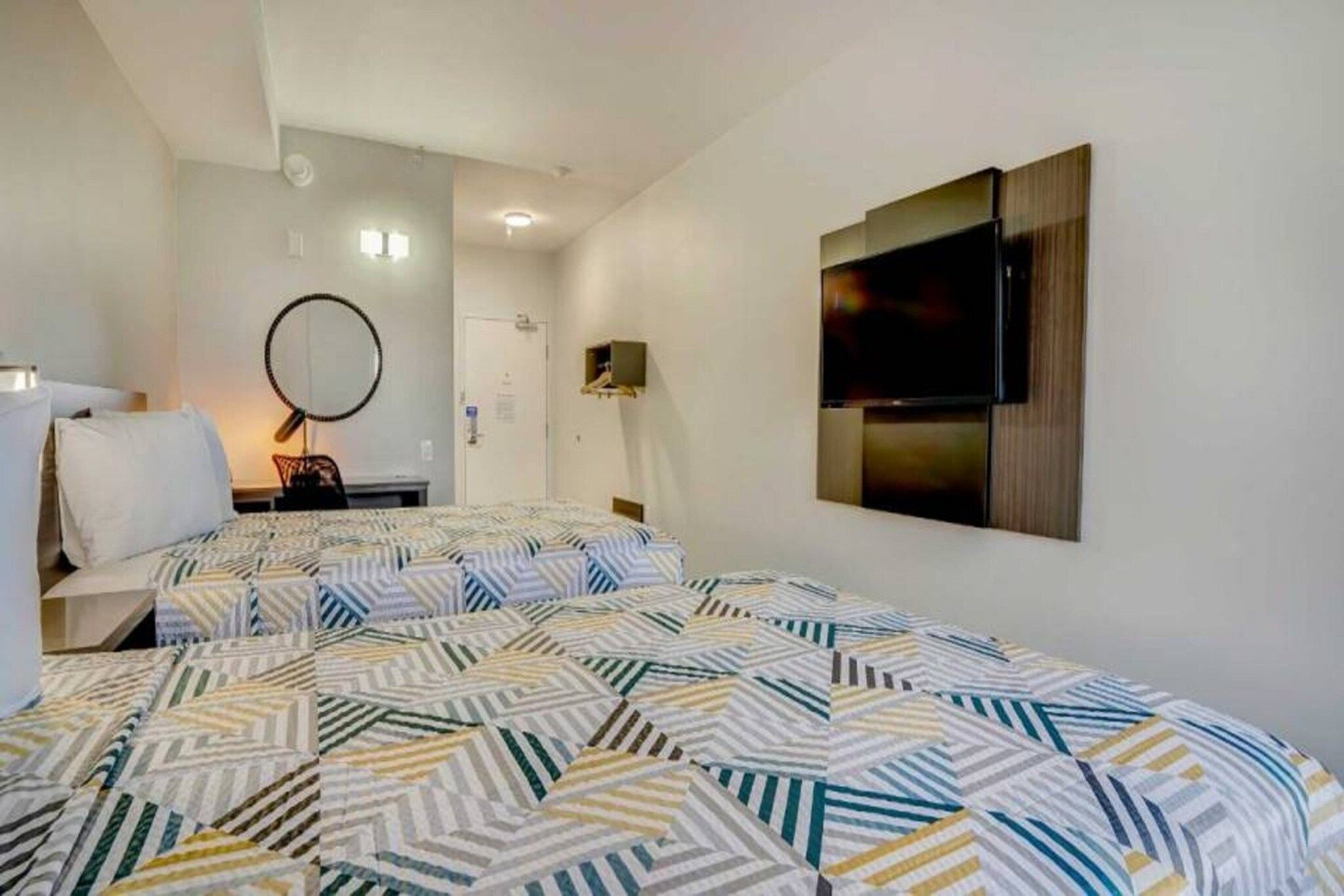 A hotel room with a bed, a TV, a desk, and a chair.