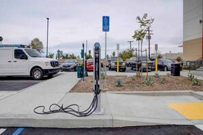 Eine Ladestation für Elektrofahrzeuge mit einem weißen Lieferwagen und mehreren parkenden Autos in der Nähe.