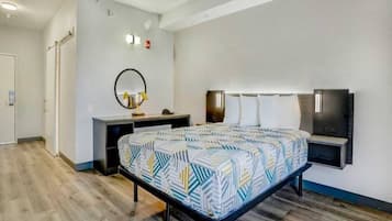 Quarto de hotel moderno com cama, escrivaninha, espelho e televisão na parede.