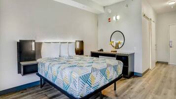 A hotel room with a bed, bedside tables, a desk, a mirror, and a wardrobe.