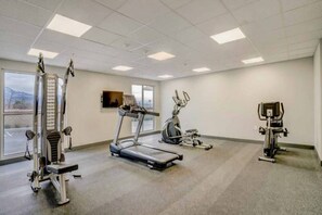 Un gimnasio con cintas de correr, bicicletas estáticas y máquinas de pesas.