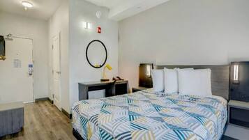 A hotel room with a bed, bedside tables, a desk, and a mirror on the wall.
