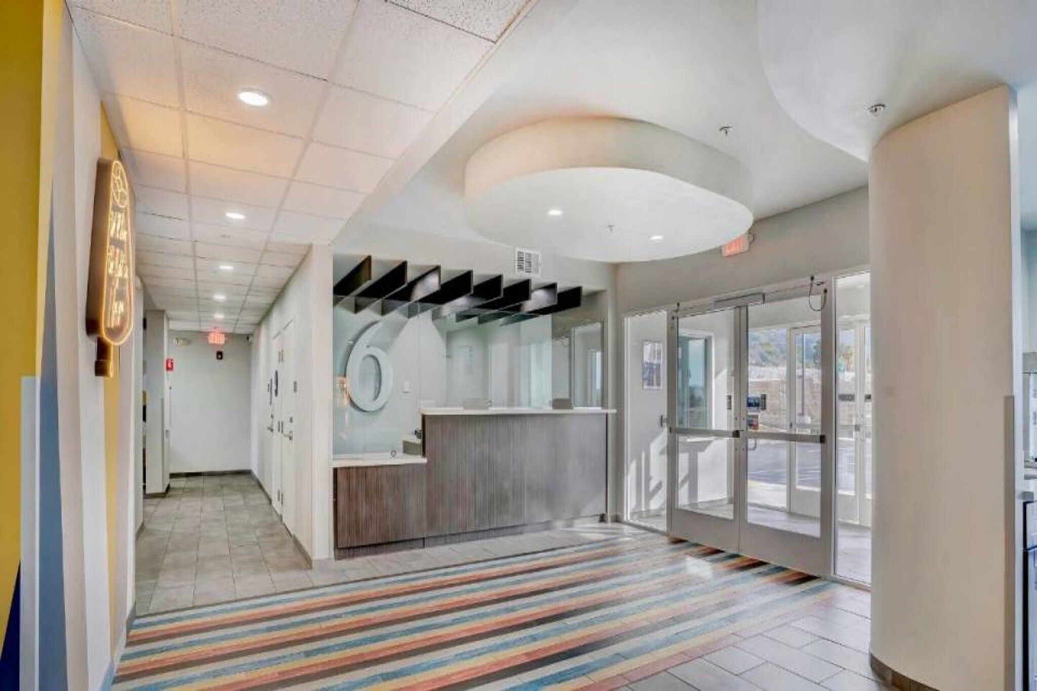 A reception area with a counter, a patterned carpet, and a glass door leading outside.