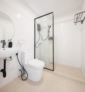 Un baño con inodoro, lavamanos y cabina de ducha.