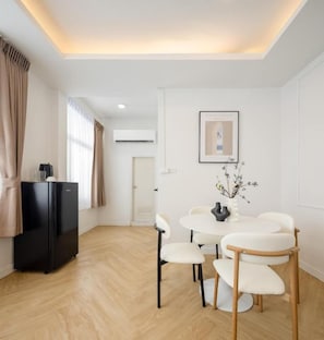 Una habitación moderna y bien iluminada con una mesa de comedor, sillas, un refrigerador negro y un cuadro en la pared.