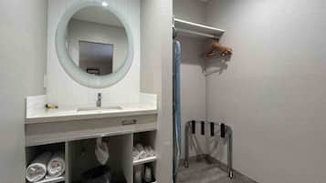 Une salle de bain avec un lavabo blanc, un miroir, un porte-serviettes et un espace douche.