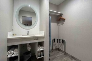 Une salle de bain avec un lavabo blanc, un miroir, un porte-serviettes et un espace douche.