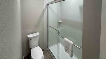A bathroom with a toilet, a glass shower enclosure, and a towel rack.