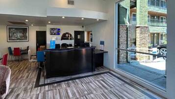 A reception area with a black counter, a television mounted on the wall, and a large window offering a view of the outside.