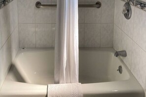 A bathtub with a shower curtain, a grab bar, and a handheld showerhead. - 1 Full Bed | Non-Smoking, Micfridge (Glendale)