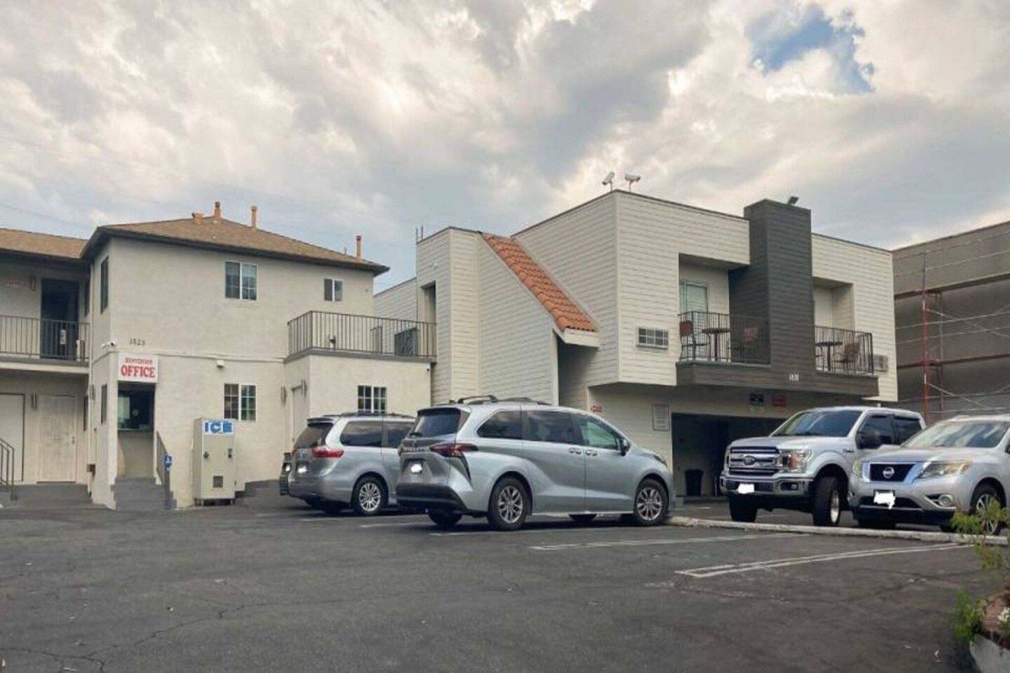 A parking lot with several SUVs, a building with a sign that reads 'OFFICE,' and a clear sky.