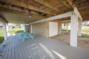 Ett takförsett utomhusområde med ett picknickbord, en garageport och en sandig yta.