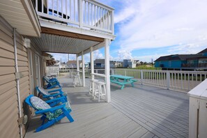 Une terrasse extérieure couverte, dotée de sièges et d’une table de pique-nique, qui offre une vue sur un quartier résidentiel.