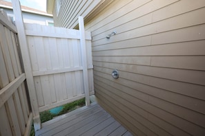 A wooden deck with a white fence and a metal faucet on the wall. - Seashell Retreat | Beachfront + Gulf Views (Galveston)