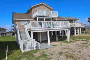 Une maison à deux étages située en bord de mer, dotée d’un balcon et d’un espace abrité.