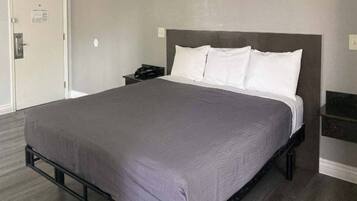 Ett standardhotellrum med en enkel säng, ett nattduksbord och en TV som är monterad på väggen.
