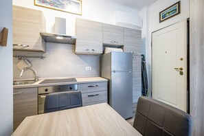 A compact kitchen with a dishwasher, a refrigerator, and a dining area with a table and chairs. - Landino 7 (Florence)