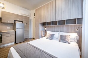 A modern bedroom with a bed, bedside tables, and a built-in wardrobe. - Landino 7 (Florence)