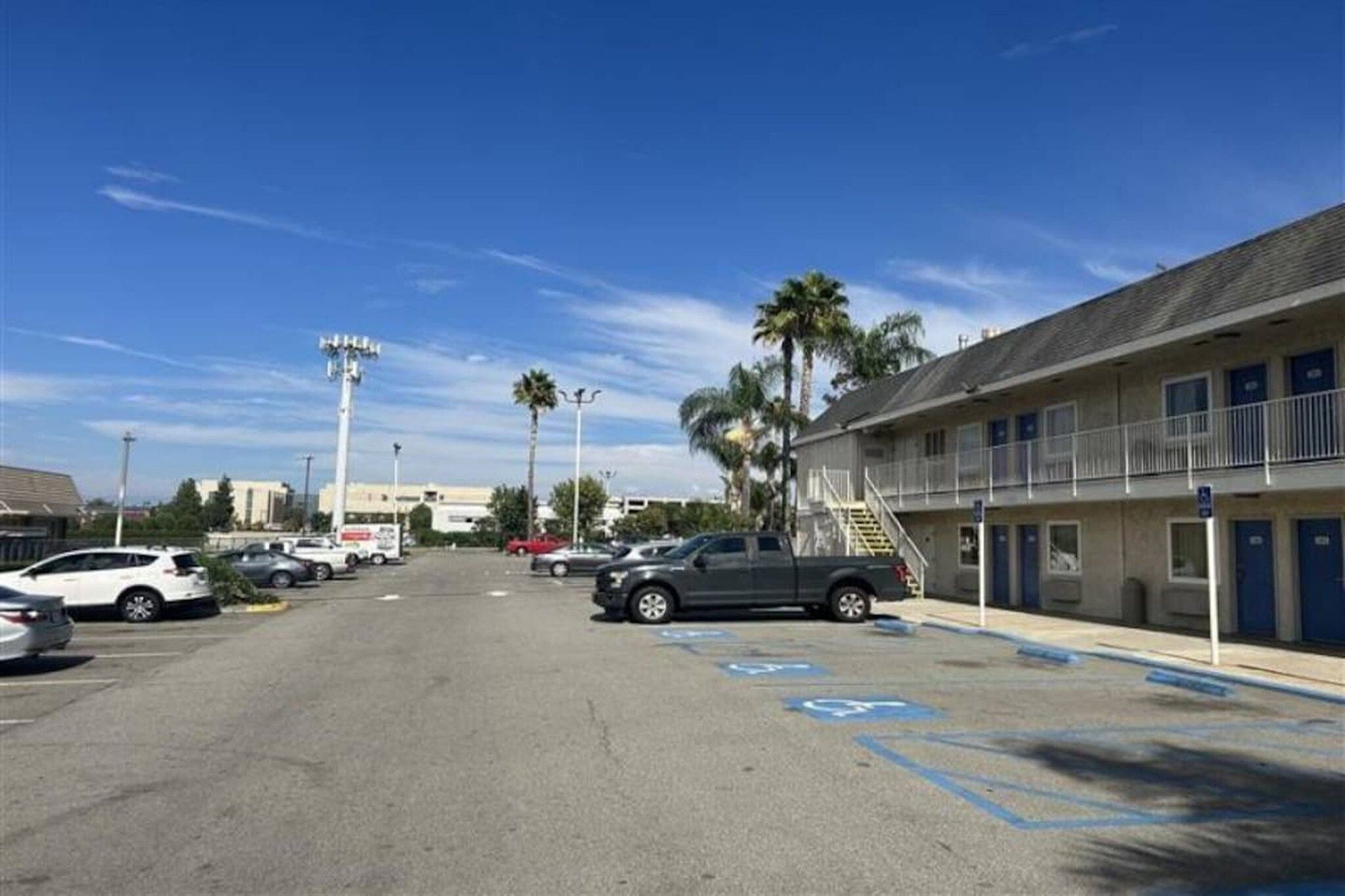 A parking lot with a building on the right, including a ramp and a blue handicapped parking space.