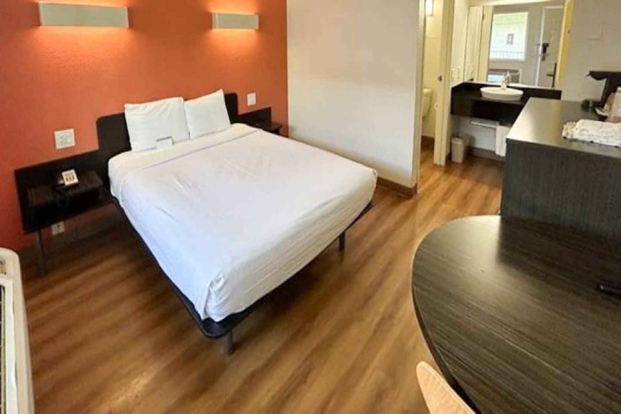 A hotel room with a bed, a desk, and a mirror.
