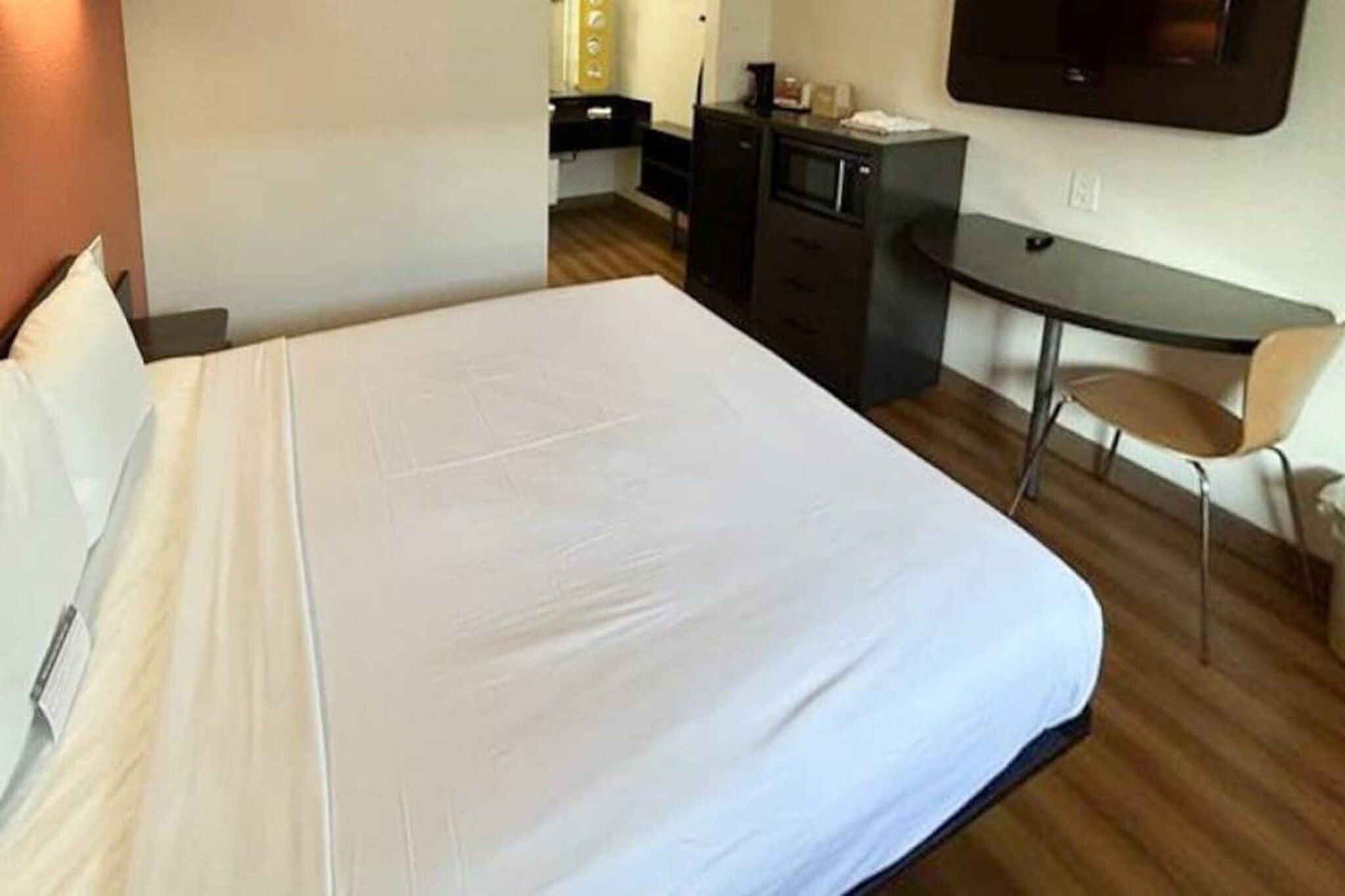 A hotel room with a large bed, a desk, a chair, and a television.