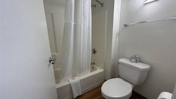 A bathroom with a bathtub, toilet, and shower curtain.