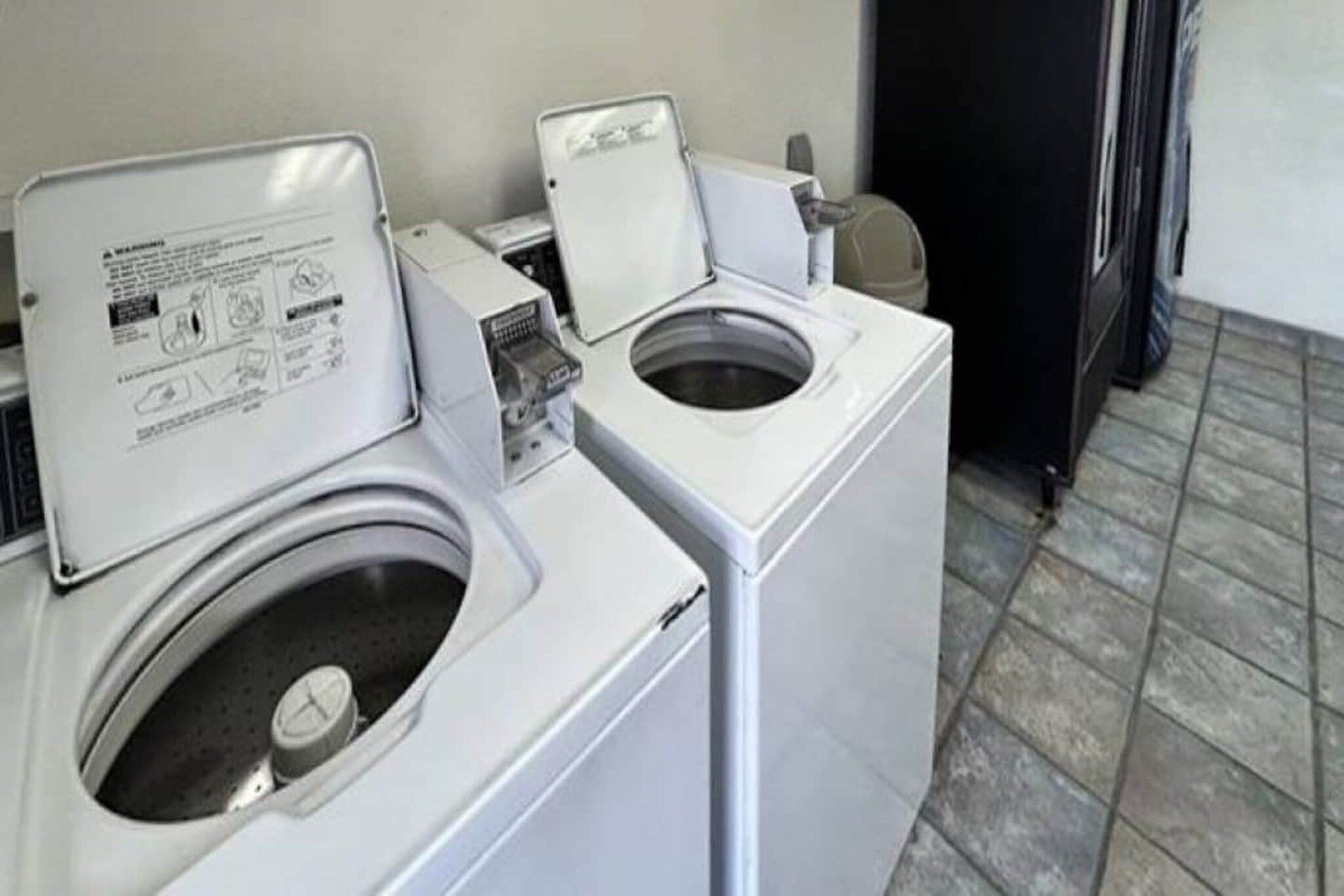 A laundry room with two front-loading washing machines and a dryer.
