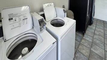A laundry room with two front-loading washing machines and a dryer.