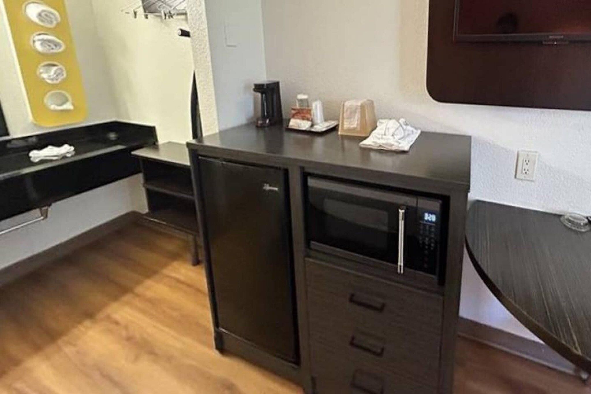 Een compacte kitchenette met een magnetron, een kleine koelkast en een wasbak.