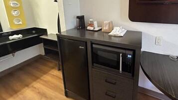Een compacte kitchenette met een magnetron, een kleine koelkast en een wasbak.