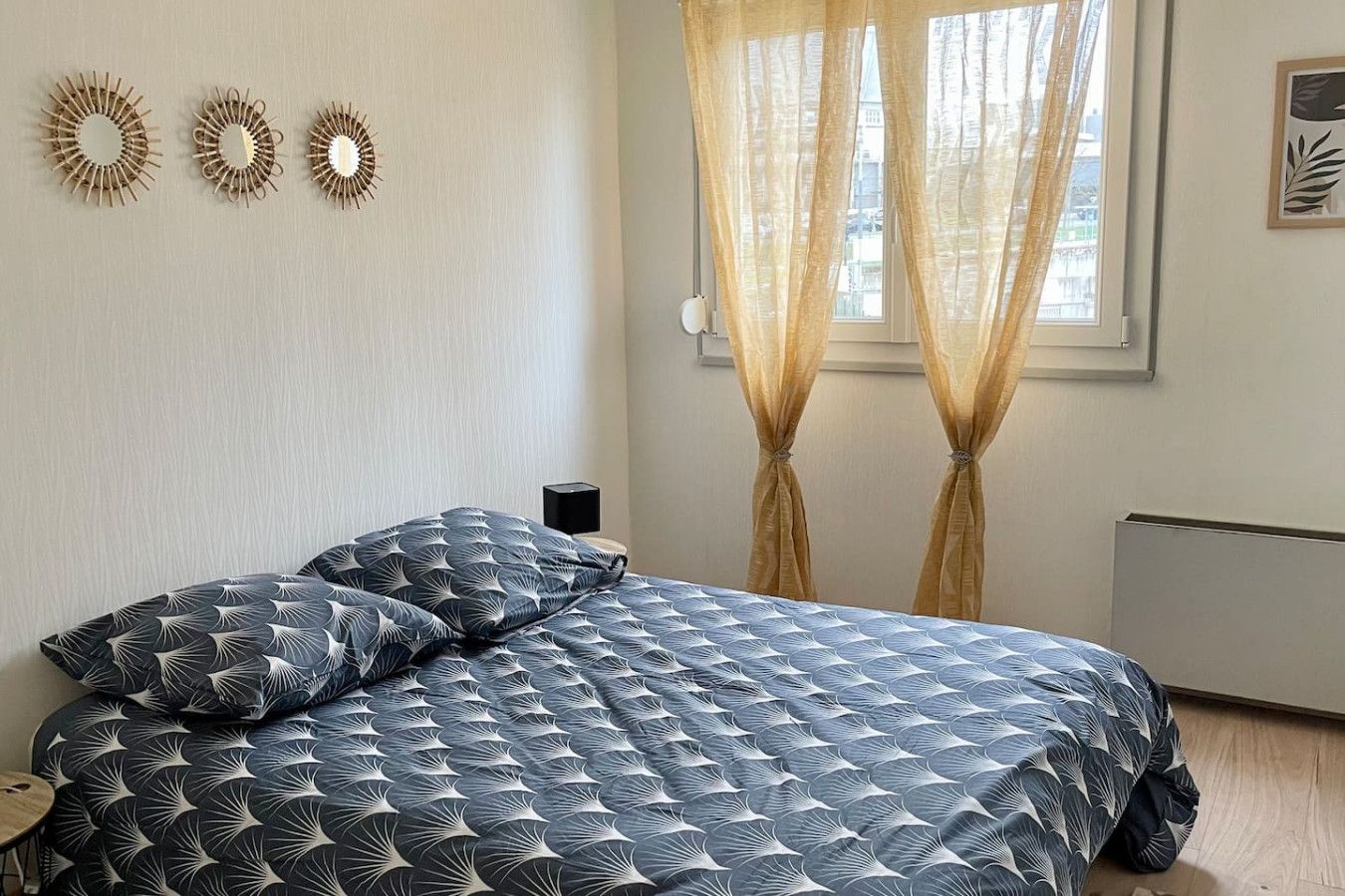 Une chambre à coucher avec un lit, des rideaux, des éléments de décoration murale et un radiateur.