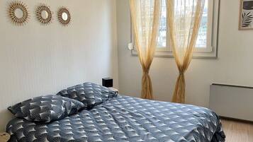Une chambre à coucher avec un lit, des rideaux, des éléments de décoration murale et un radiateur.