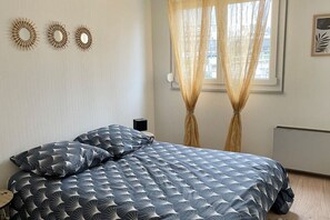 Une chambre à coucher avec un lit, des rideaux, des éléments de décoration murale et un radiateur.