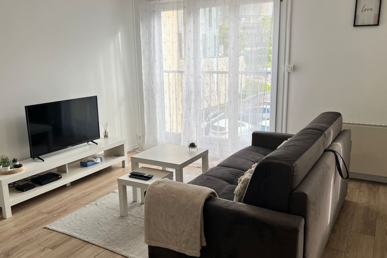A modern living room with a flat-screen TV, a sofa, a coffee table, and a small side table.