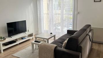 Een moderne woonkamer met een flatscreen televisie, een bank, een salontafel en een klein bijzettafeltje.