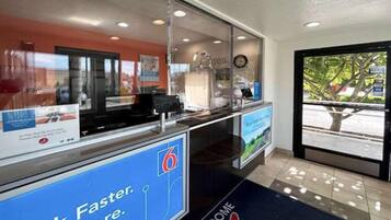 A reception area with a digital display, a welcome mat, and a view of the outside.