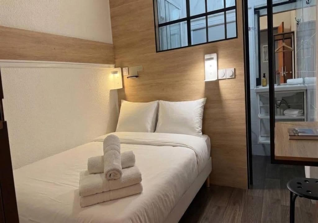 Une chambre d’hôtel avec un lit, une table de chevet, un miroir et vue sur la salle de bain.