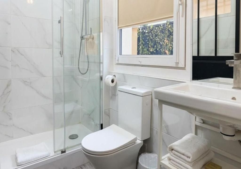 Un baño con ducha de vidrio, inodoro y lavamanos con espejo.