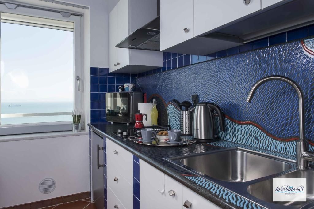 Une cuisine avec vue sur la mer, un évier en acier inoxydable et une fenêtre.