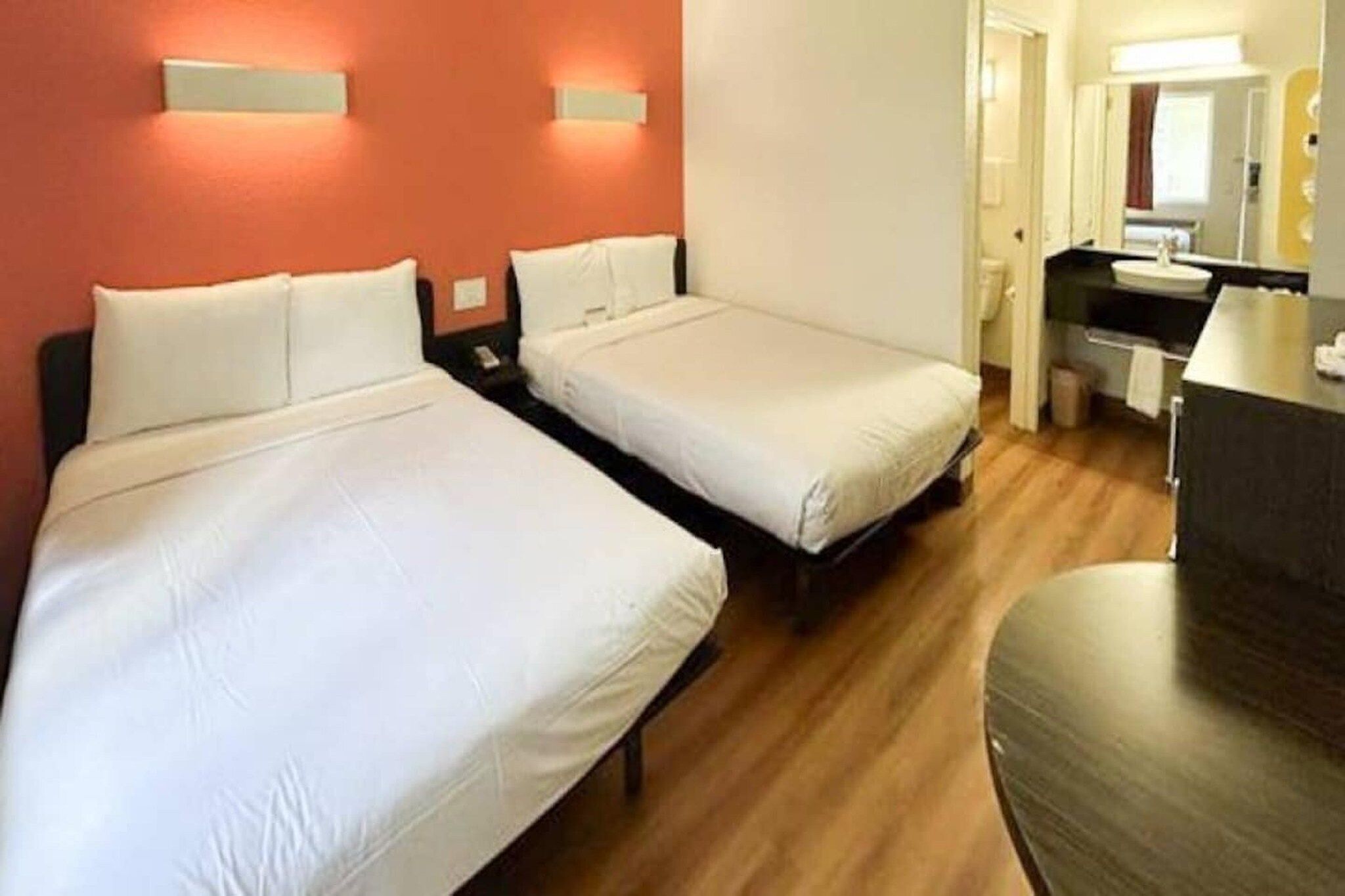 Een hotelkamer met twee éénpersoonsbedden, een bureau, een stoel en een spiegel.