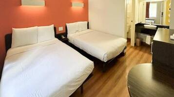 Een hotelkamer met twee éénpersoonsbedden, een bureau, een stoel en een spiegel.