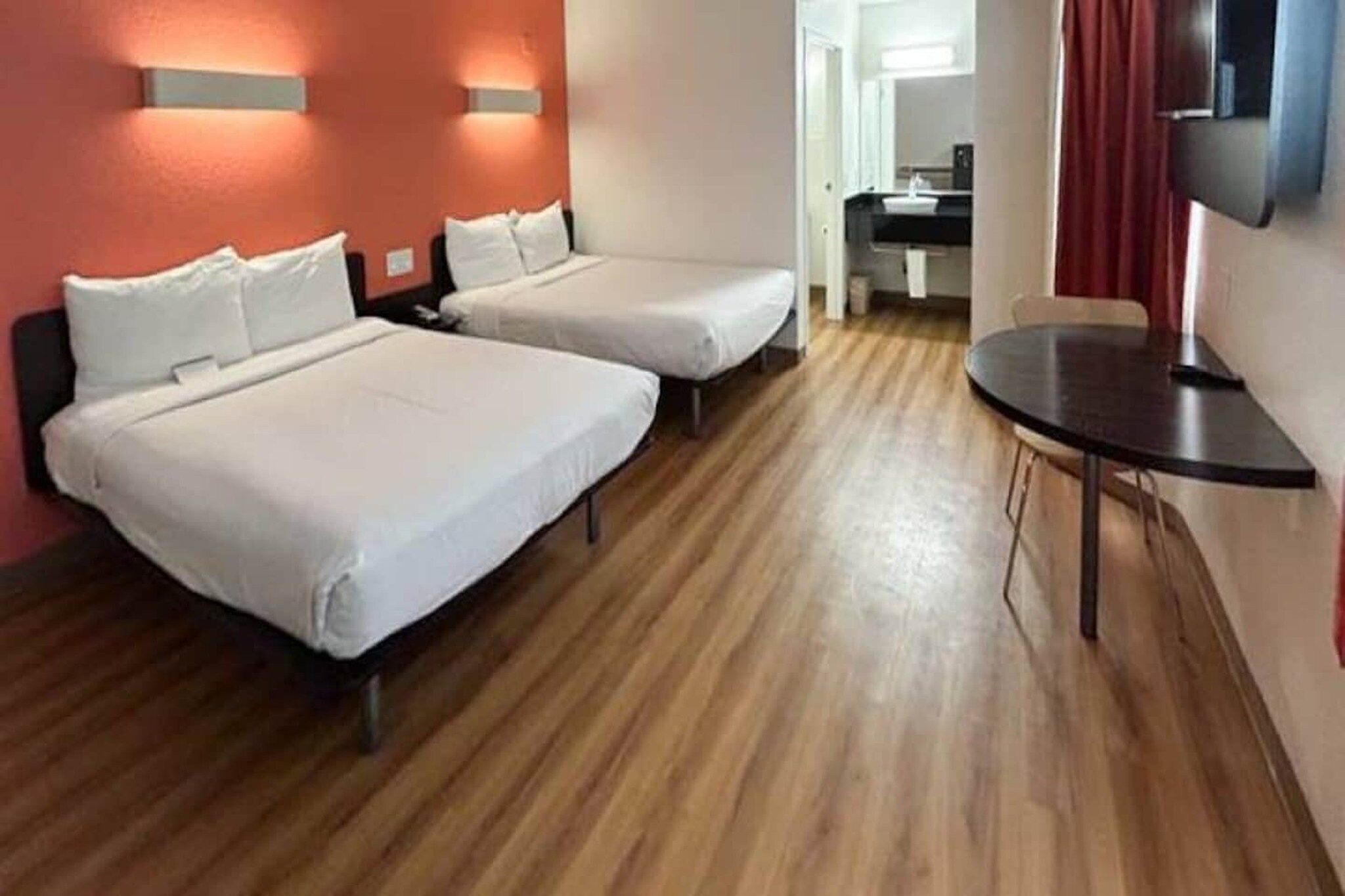 Een hotelkamer met twee bedden, een kleintje tafeltje en een televisie.