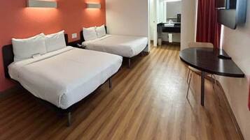 Een hotelkamer met twee bedden, een kleintje tafeltje en een televisie.