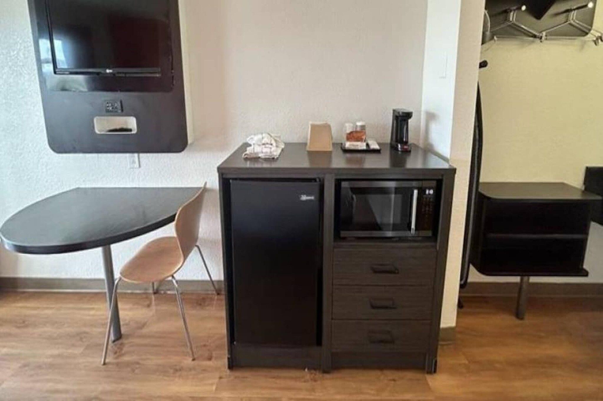 A compact kitchenette with a microwave, a small refrigerator, and a coffee maker on a countertop.