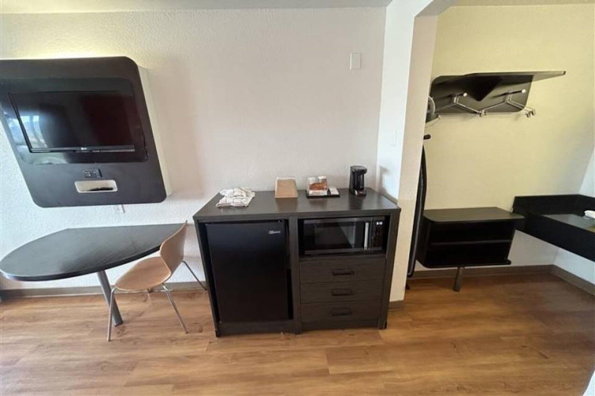 Een kleine kamer met een bureau, stoel en een wandgemonteerde flatscreen-tv.